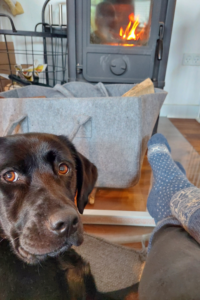 Skandinavische Wollsocken vor einem Morsö Ofen mit Hund – gemütlicher Hygge-Moment zuhause.